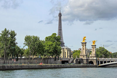 Eiffel tower by seine river against sky