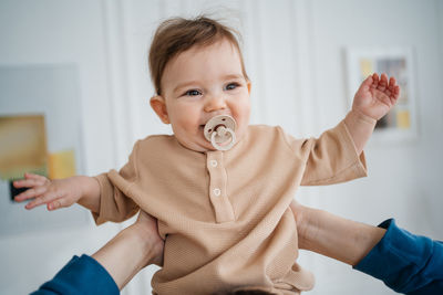 Joyful child with a pacifier in his father's arms