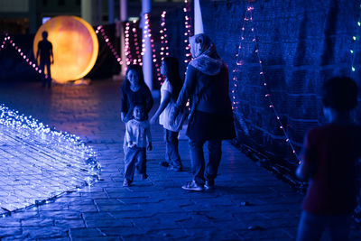 People walking on illuminated footpath at night