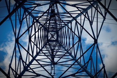 Low angle view of electricity pylon against blue sky