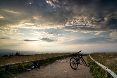 Bicycle on road against sky during sunset