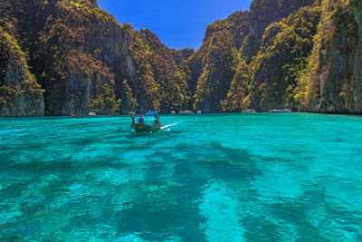 People on boat in sea against mountains