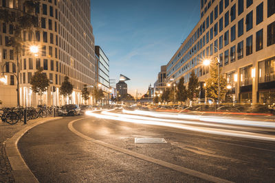 Light trails on city street by buildings at night