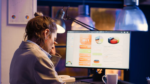 Side view of young woman using mobile phone in office