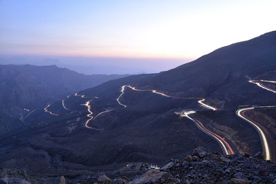 View of light trails on mountain road during dusk