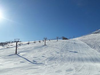 Snow covered land against clear blue sky