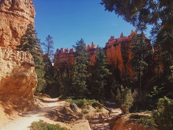 Rock formations by trees against sky