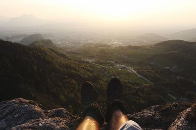 Low section of man against mountains during sunset