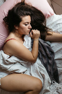 Woman sleeping with blanket on bed at home