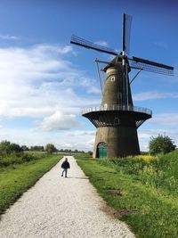 Rear view of boy standing on footpath by traditional windmill