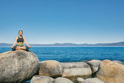 Young woman practicing yoga on lake tahoe in northern california.