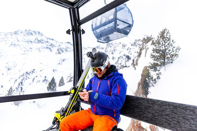 Man using mobile phone while sitting in cable car
