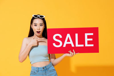 Full length of woman standing against yellow background