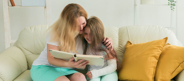 Young woman using mobile phone while sitting on sofa at home