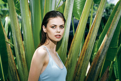 Portrait of young woman standing against plants