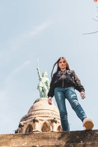 Low angle view of woman sitting against sky