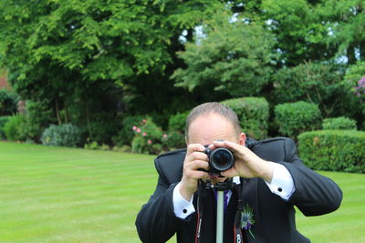 Man photographing through digital camera in garden