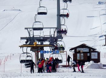 People in ski lift by snowcapped mountain