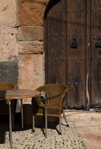 Outdoor emply table and chairs against old wooden door in sepulveda, spain