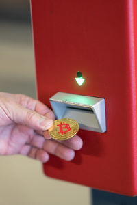 Human hand inserting a bitcoin into a vending machine. bitcoins are cryptocurrency