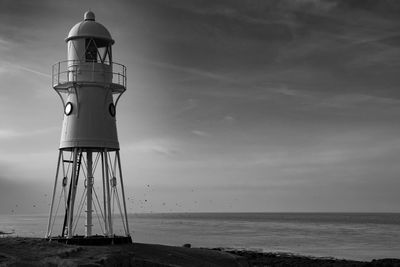 Lighthouse by sea against sky