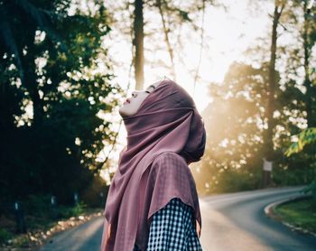 Woman with eyes closed standing on road