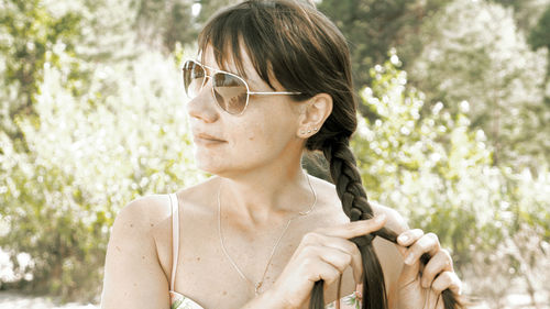 Woman wearing sunglasses against trees