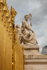 Low angle view of angel statue against cloudy sky