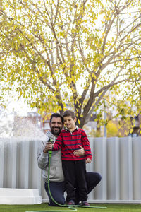 Father and son watering the grass on their home