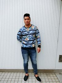 Portrait of young man standing against wall