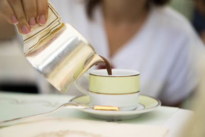 Close-up of hand pouring coffee in cup