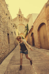 Playful woman walking on footpath by church