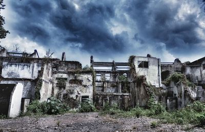 Abandoned building against cloudy sky