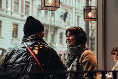 Smiling female friends talking while sitting in cafe during winter