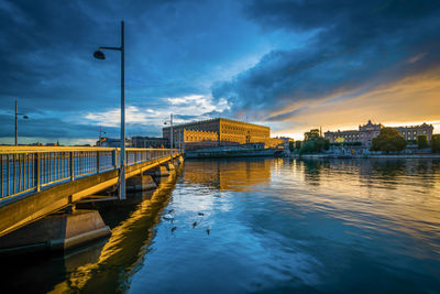 Bridge over river against sky in city at dusk