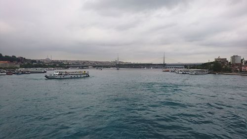 View of suspension bridge over river against cloudy sky