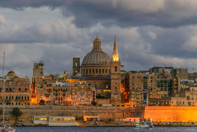 Buildings in city against cloudy sky