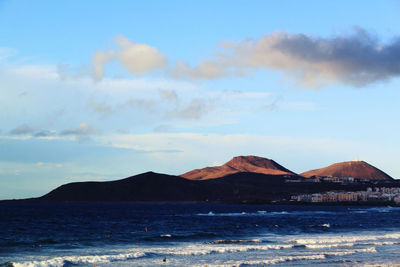 Scenic view of sea and mountains against sky