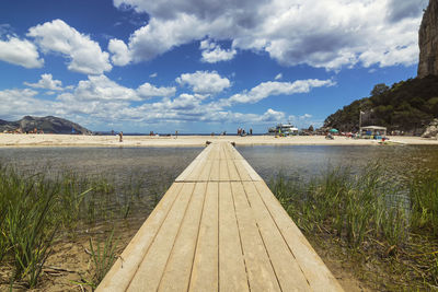 Surface level of footpath by sea against sky