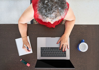 High angle view of woman using laptop on table