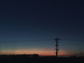 Low angle view of silhouette electricity pylon on field against clear sky