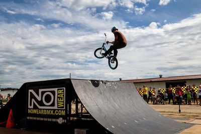 Man jumping with bicycle against sky