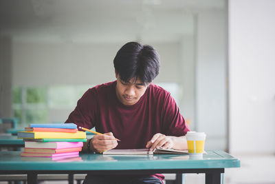 Man writing at table in cafeteria