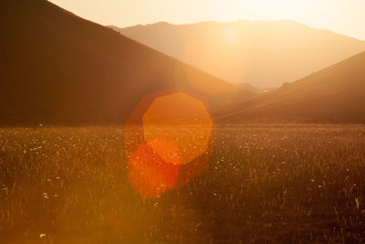 Idyllic shot of landscape against silhouette mountains during sunset