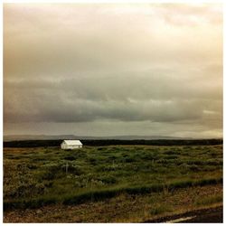 Scenic view of grassy field against cloudy sky