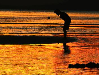 Silhouette man on beach against sky during sunset