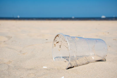 Close-up of abandoned bottle on beach