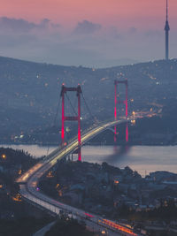 Aerial view of illuminated bridge amidst mountains against sky at dusk