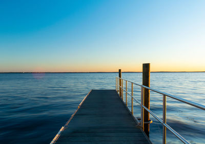 Pier over sea against clear sky during sunset