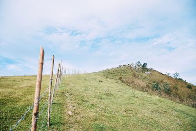 Wooden fence on field against sky